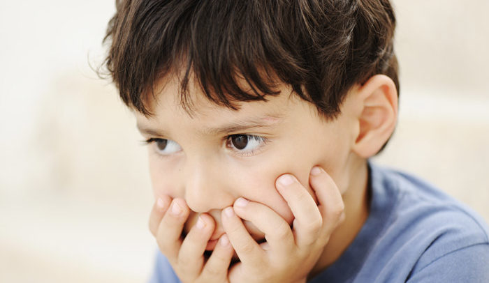 young boy scared with hands cupping his mouth